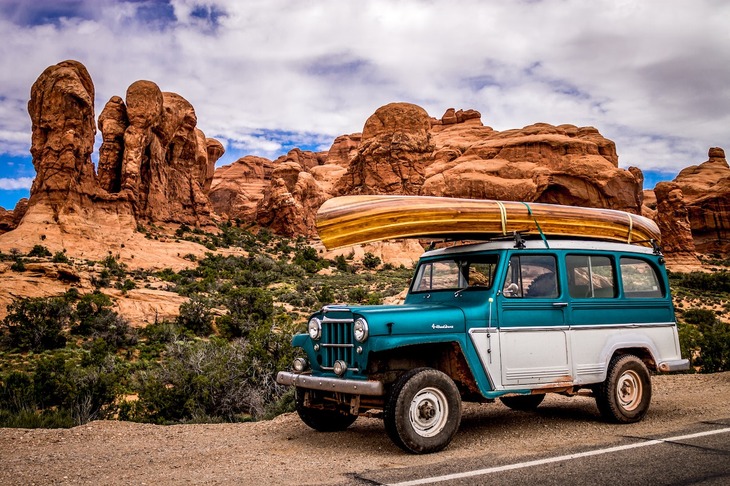 A car with a canoe on top in a canyon environment.